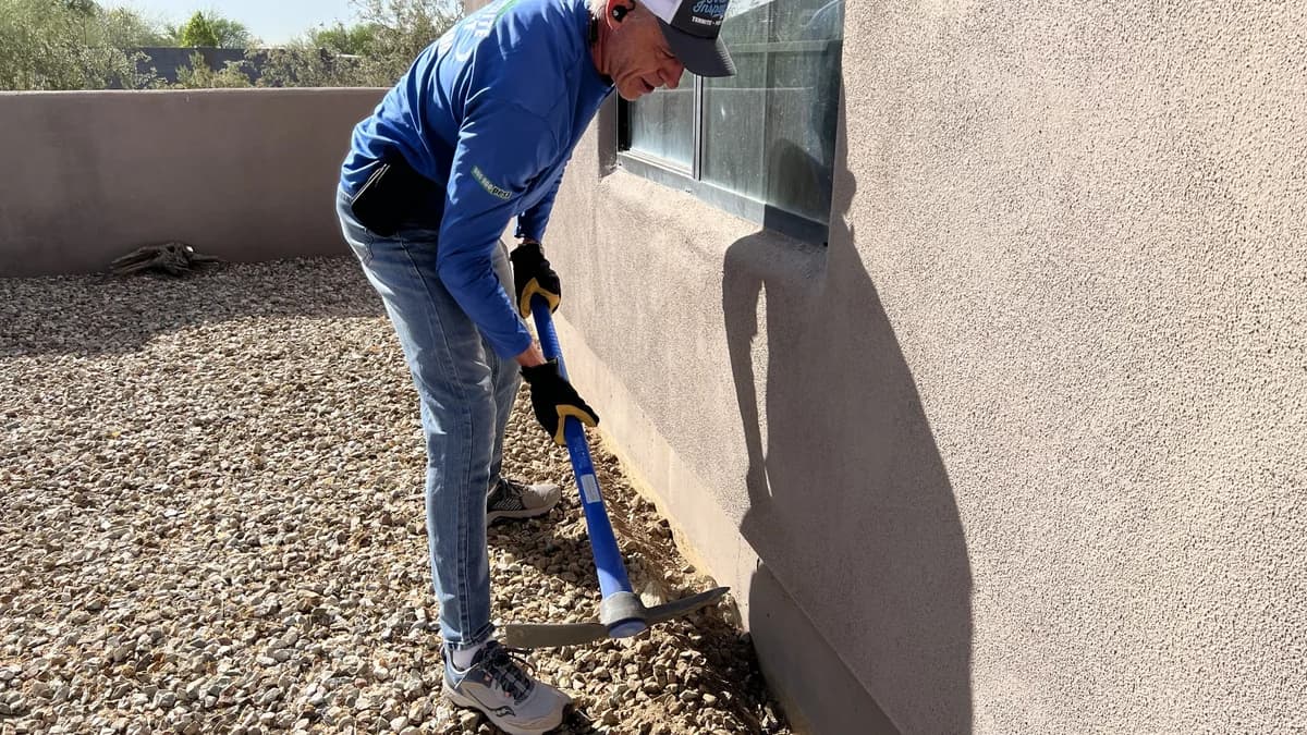 Inspecting the stem wall and soil contact points of an Arizona home for termite mud tubes